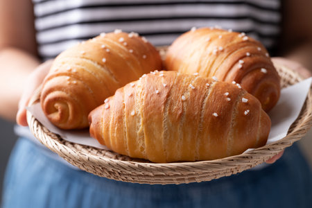 Salt bread (Shio pan) with sea salt flakes in a basket holding by woman hand.