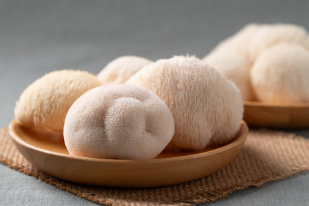 Fresh Lion's Mane mushroom,(Hericium erinaceus) on wooden plate, known for nootropic benefits and...