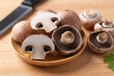 Fresh crimini mushroom or baby bella mushroom on wooden plate prepared for cooking