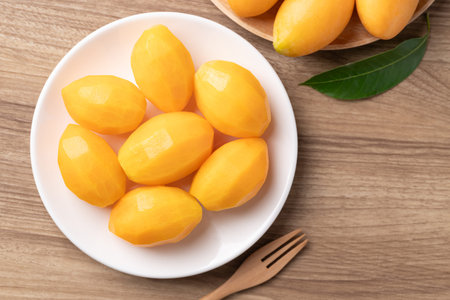 Fresh peeled Marian plum (Mayongchid) on a white plate ready to eat, Thai tropical fruit in summer...