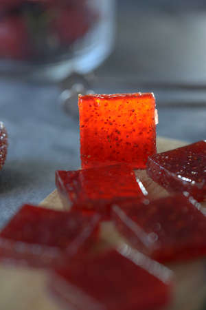 On a wooden board, strawberry marmalade, cut into cubes, with strawberries.