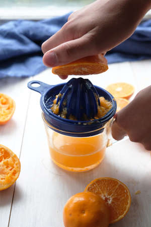 Freshly squeezed orange juice in a cup. fresh fruits of oranges and tangerines on a white table.