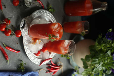 On the table are glasses with tomato juice, ice and tomatoes.の写真素材