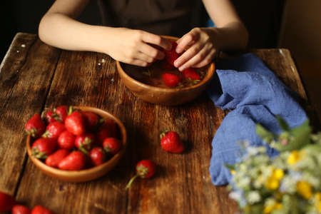 A lot of ripe red strawberries in children's palms. The child washes strawberries in clean water.
