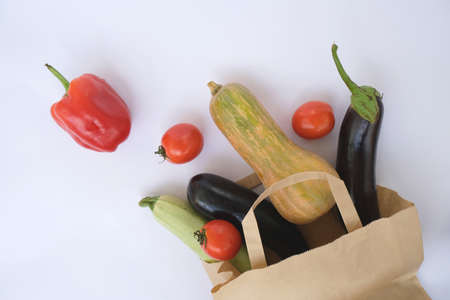 A paper bag with scattered vegetables (zucchini, peppers, tomatoes, eggplants, beets, pumpkin).