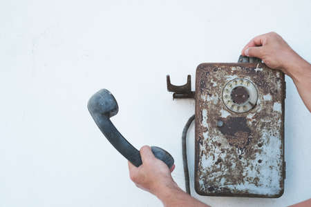 An old telephone hangs on the wall, a man's hand picked up the receiver.の写真素材
