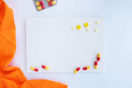 Creative mockup of pills and capsules on white background and orange cloth. Covid-19 or coronavirus...