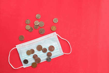 On a turquoise background, a surgical mask and money. Russian coins.の写真素材