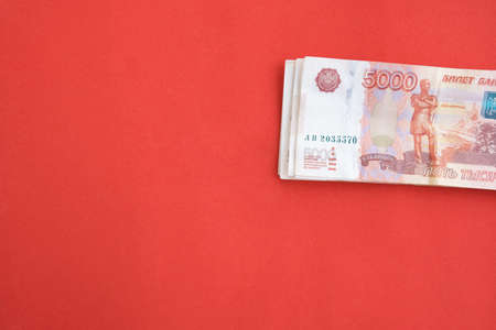 Money in rubles close-up, banknotes of five thousand rubles, on a red background.