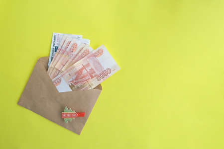On a yellow background, an envelope with money, Russian five thousandth rubles. Economy concept, money distribution. Gift for the new year.の写真素材