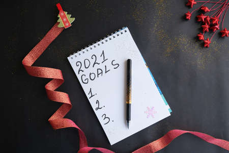 On a dark table, there is a notebook of goals for 2021, with New Year's decorations. New year concept.の写真素材