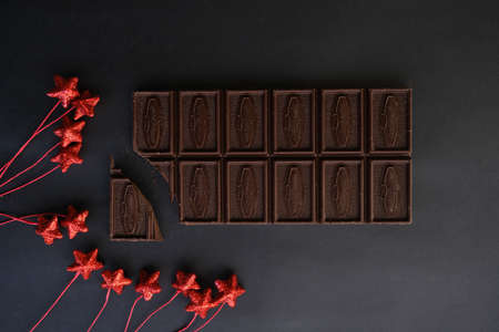 On a dark background, bitter chocolate and New Year's decorations (red stars).