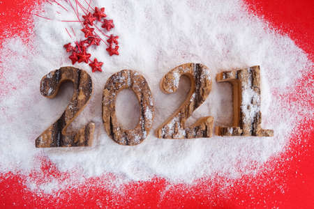 Wooden numbers 2021 year on a red background on snow.