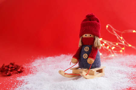 Christmas decoration of a girl on a sleigh, rolling in the snow, on a red background.の写真素材