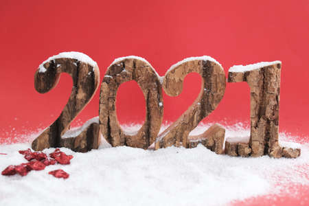Wooden numbers 2021 year on a red background on snow.