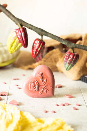 Heart shaped pink chocolate handmade. Chocolate bar on a background of cocoa fruits. View from...