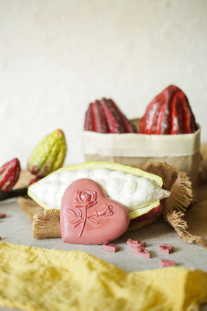 Heart shaped pink chocolate handmade. Chocolate bar on a background of cocoa fruits. View from...