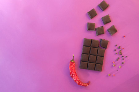 Creative mockup made of chocolate, red pepper on a pink background. Flat lay. Food concept.の写真素材