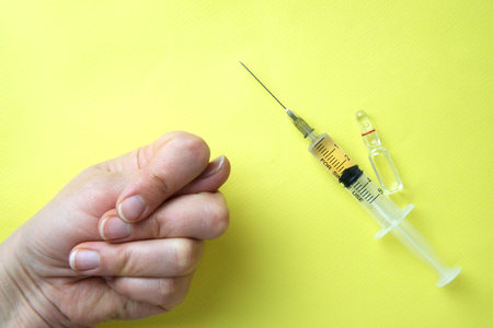 Syringe with vaccine and a child hand with a call to refuse vaccinationの写真素材