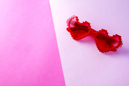Pink romantic glasses in the shape of a heart against a pink and crimson background. Greeting card,...