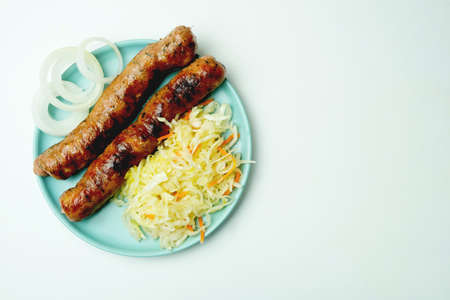 Grilled sausage with spices on a plate with white background.