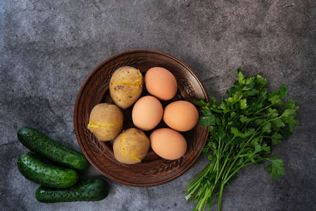 Ingredients for okroshka or salad are herbs, eggs, cucumbers, potatoes. top view on a dark background.の写真素材