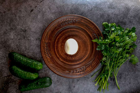 On a plate there is an egg, next to cucumbers and herbs. Diet concept. Balanced useful components of...