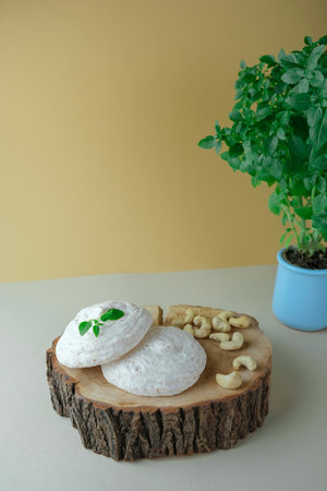 Walnut cookies and basil in a shell on a beige background. Soft light. Commercial filming.