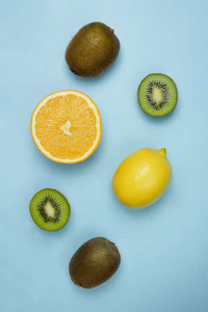 Creative layout of fruits, kiwi, orange and lemon on a bright blue background. Healthy food minimal concept. Flat lay.の写真素材