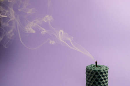 Smoke from a burning candle on a purple background. The concept of aromatherapy and relaxation.の写真素材
