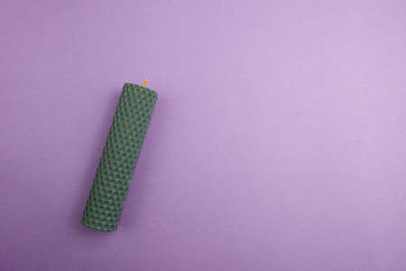 Green wax candle on purple background, top view. Space for textの写真素材
