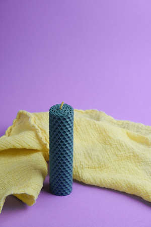 Aroma candle and yellow cloth on violet background, space for textの写真素材