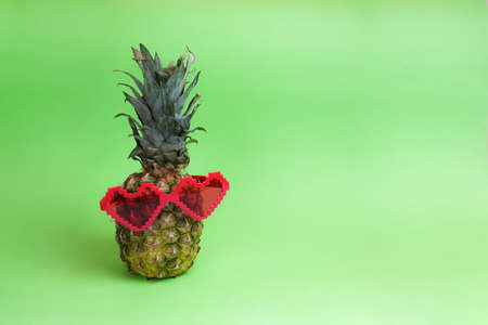 Funny background. Pineapple with funny heart shaped glasses, vacation, summer conceptの写真素材