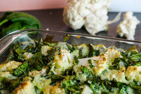 Oven baked cauliflower recipe. Baked cauliflower steaks with herbs and spices on a baking sheet on a black background.の写真素材