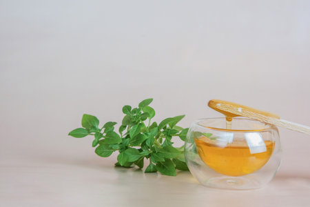 Depilation and beauty concept - sugar paste or wax, honey for hair removal drips from wooden wax sticks in a jar on a floral backgroundの写真素材