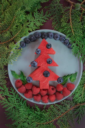 Creative christmas mockup funny edible tree, christmas breakfast idea for kids from watermelon. Flat lay. Food concept. Christmas and New Year 2023 food background.の写真素材