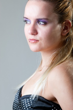 Blonde model with stronk purple makeup and a piercing on the lip looking to the sideの写真素材