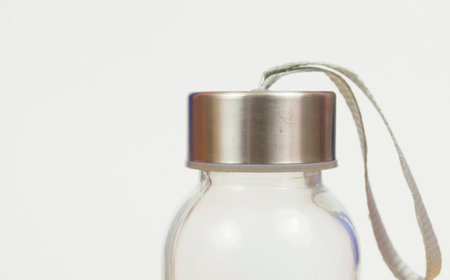 Glass bottle with lid stainless with gray rope used for handle isolated on white background....