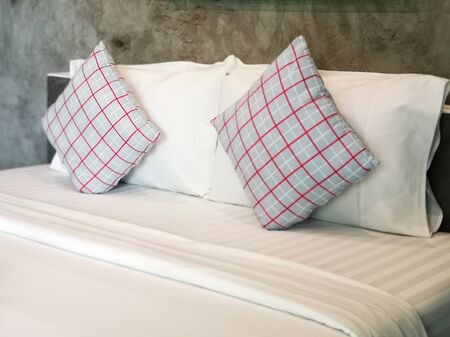 The gray square pillows red checkered pattern on a white bed set.