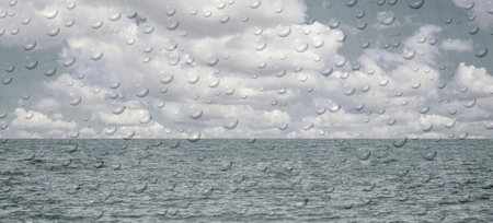 Water droplets on the glass on a rainy day on the blur beach background.の写真素材