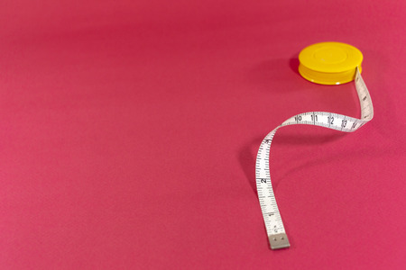 Measuring tape on red background. Tailor measure tape.の写真素材