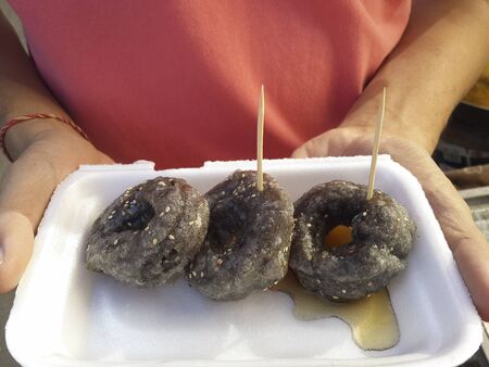 black donuts topped with syrupの写真素材