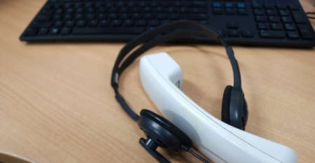 Close-up of headset and computer keyboard on table in call centerの写真素材