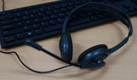 Headset with computer keyboard on wooden table. Call center support.の写真素材
