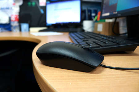 Close-up of black computer mouse on wooden desk in office.の写真素材