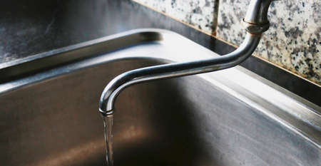 Stainless steel faucet in kitchen, close up.の写真素材
