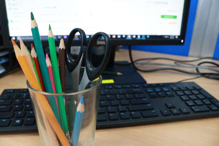 Pencils, scissors in a glass and computer monitor on the table.の写真素材