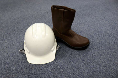 Safety helmet and boots on a gray carpet. Safety equipment for work.の写真素材