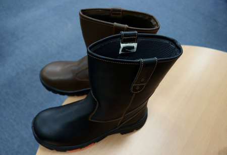 Men's black leather boots with a belt on a gray background.の写真素材