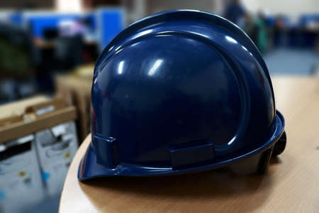 Blue safety helmet on a wooden table in a warehouse. Industrial background